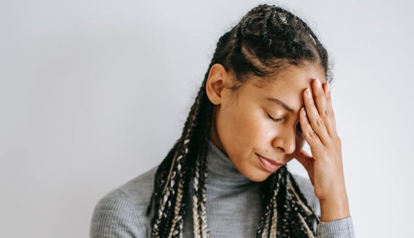 upset black woman touching head on light background